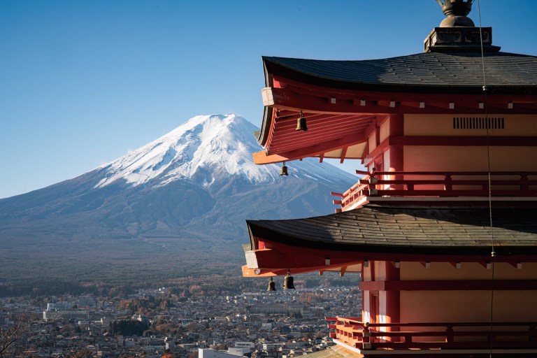 Red pagoda with snow-capped Mount Fuji in the background, under a clear blue sky.