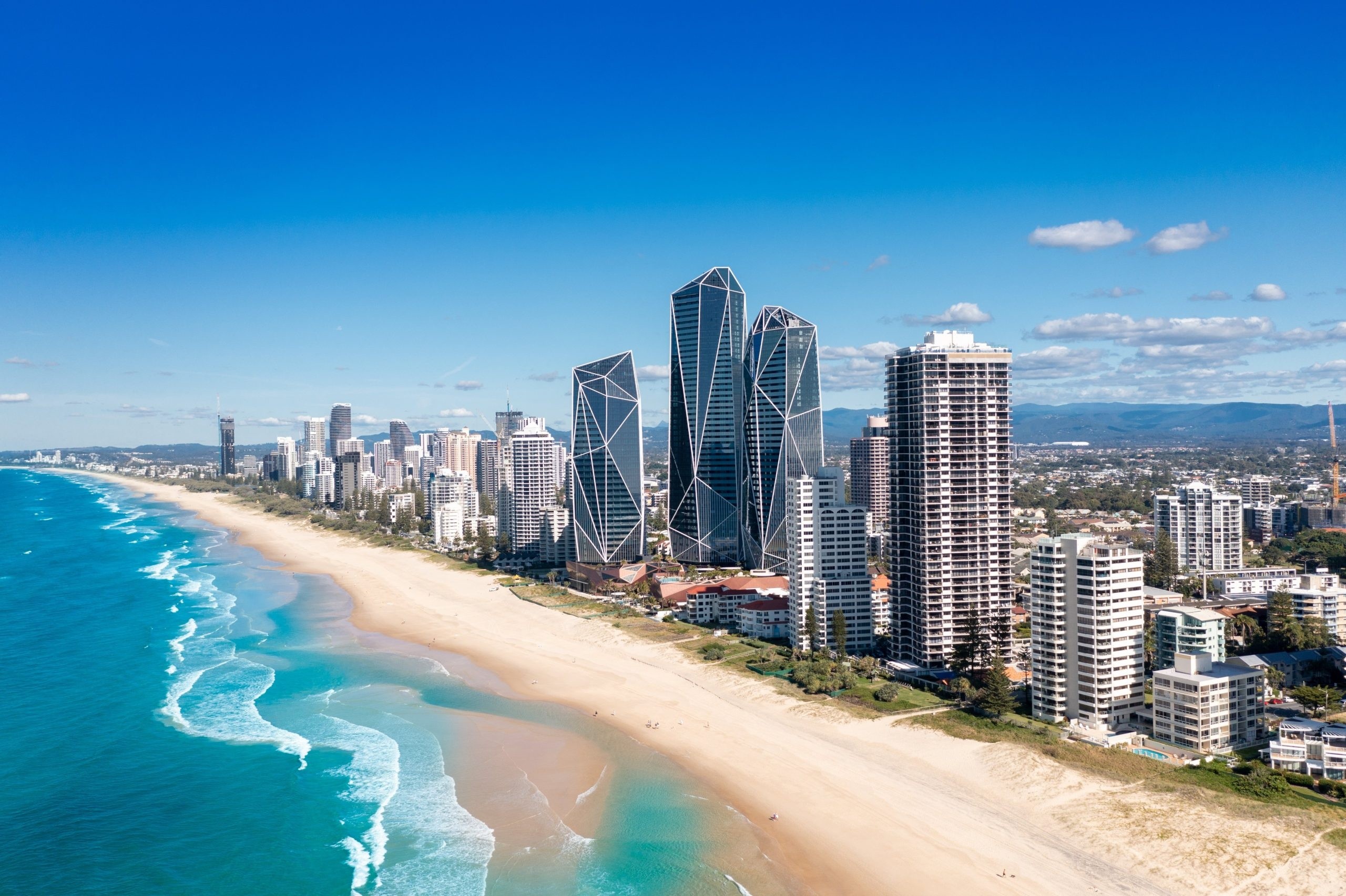 Aerial view of beachfront city with tall buildings and clear blue skies.