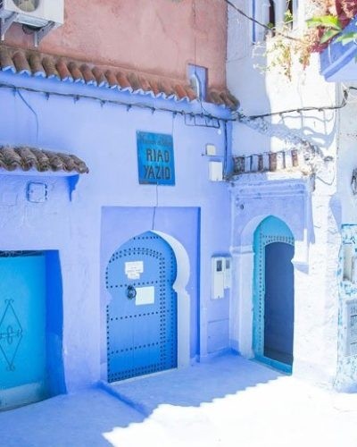 Blue-painted building with arched doors and sign 'RIAD YAZID'